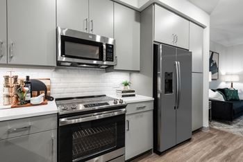 a kitchen with gray cabinets and stainless steel appliances